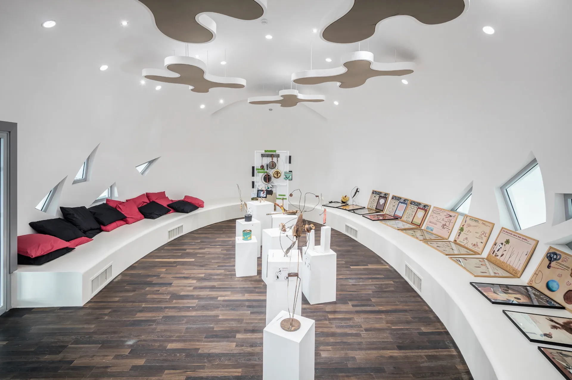 Salle d’exposition circulaire avec assises intégrées et mobilier scénographique