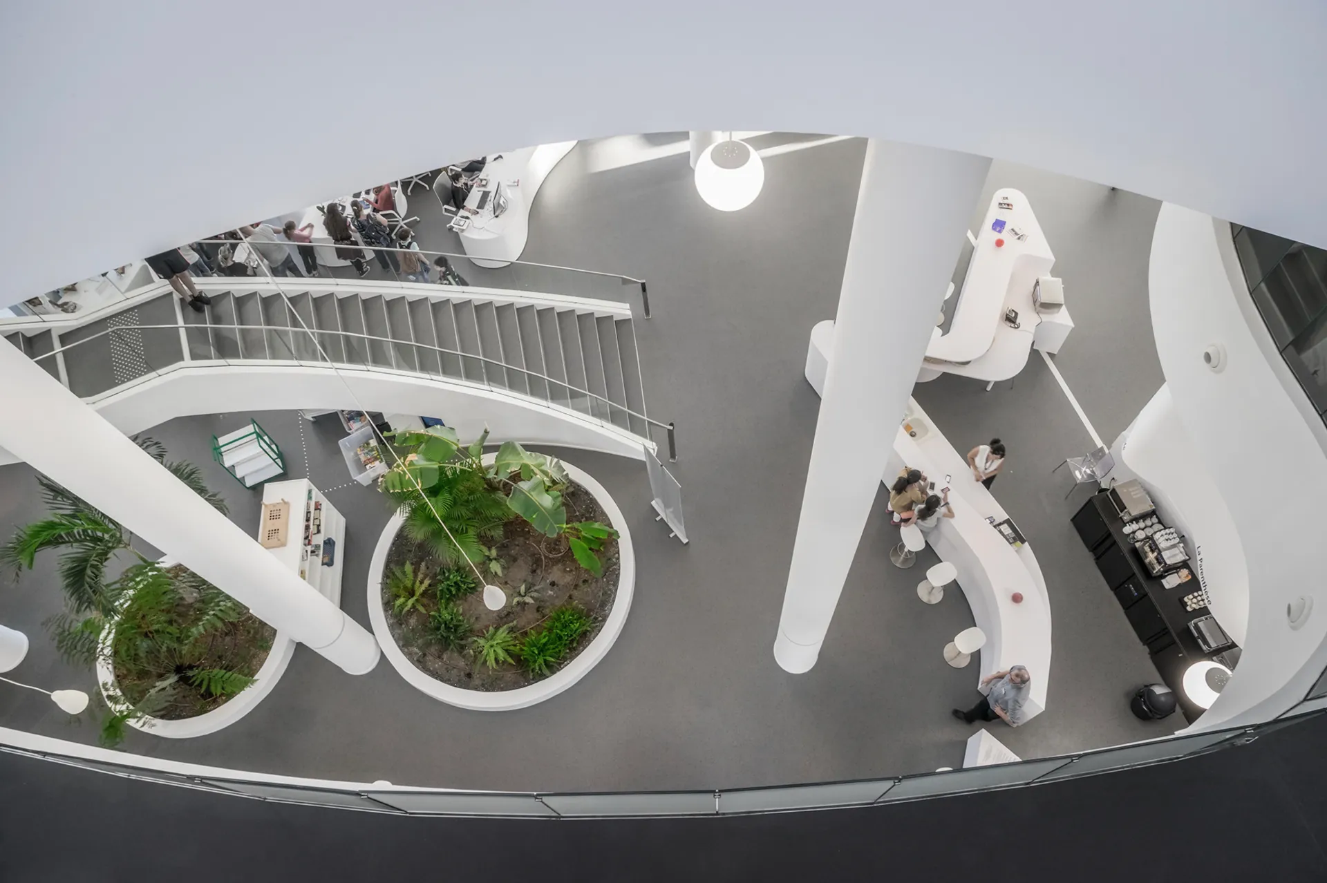 Vue plongeante d’un hall culturel avec escalier et mobilier d’accueil